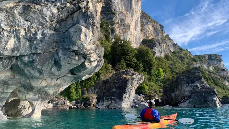Kayakers paddling into a marble cave on a marble caves Chile kayak tour of Las Capillas de Marmol, Puerto Rio Tranquilo